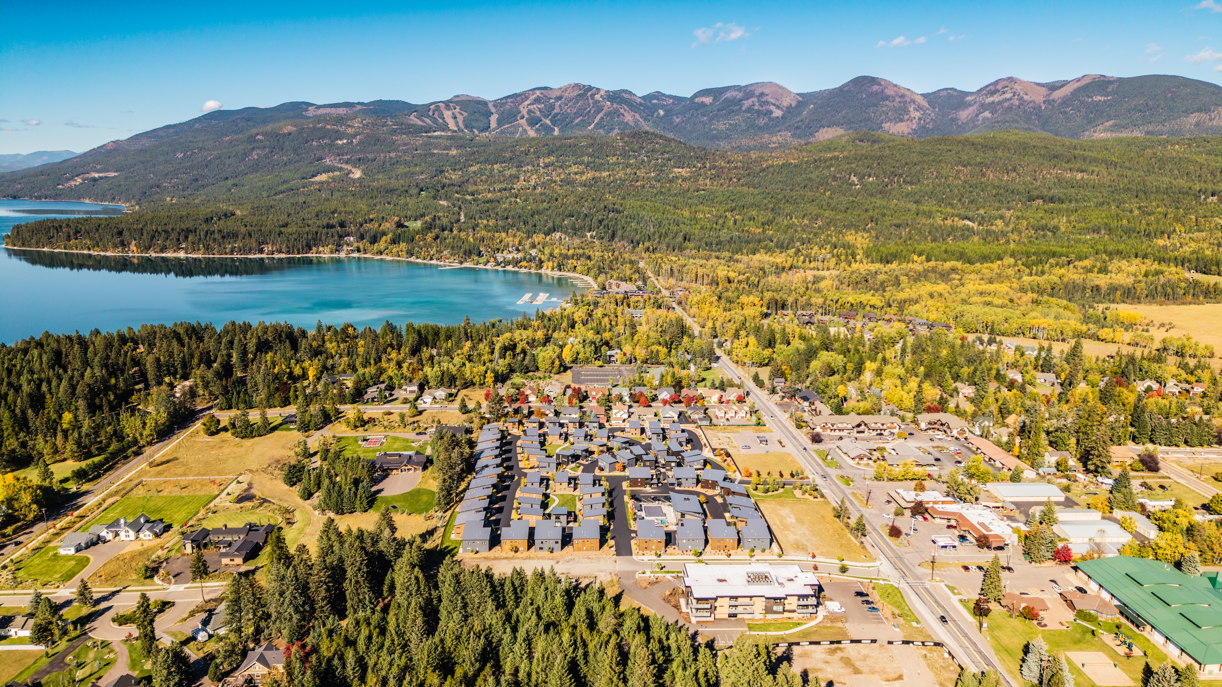 Aerial view of a blue lake, autumn trees, neighborhoods, and a forested mountain ridge
